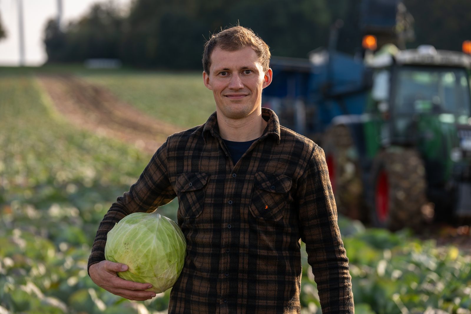 Business Fotografie – Landwirt mit Weißkohl vor Traktor im Abendlicht